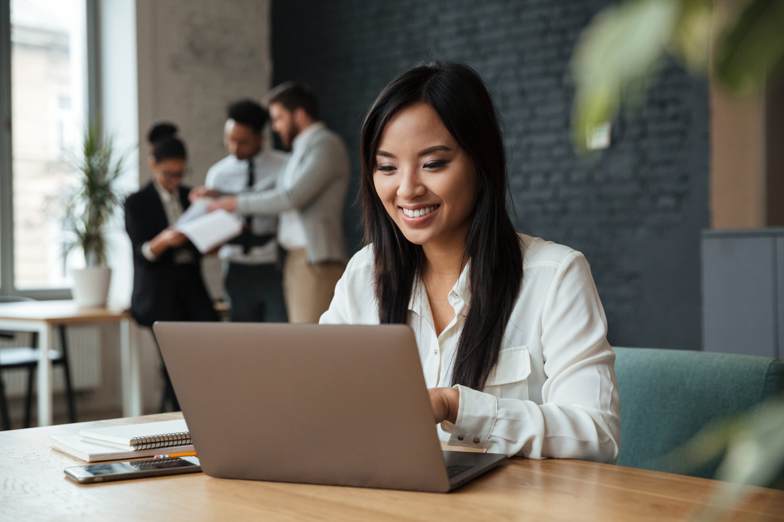 Cheerful young asian business woman using laptop loan
